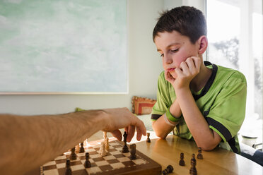 Abgeschnittene Hand des Vaters, der mit seinem Sohn zu Hause am Tisch Schach spielt - CAVF53607
