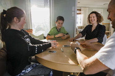 Glückliche Familie beim Pokerspiel am Tisch zu Hause - CAVF53614