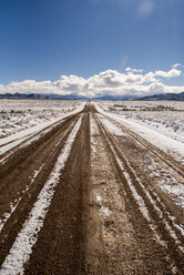 Dirt road amidst snowy desert against sky during winter - CAVF53619