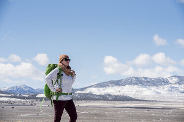 Weibliche Wanderin mit Rucksack steht in der Wüste gegen den Himmel im Winter - CAVF53621