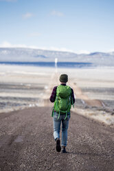 Rückansicht eines Wanderers mit grünem Rucksack in der Wüste - CAVF53624