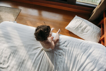 Hoher Winkel Blick auf hemdsärmelig Baby Mädchen sitzt auf Bett zu Hause - CAVF53647