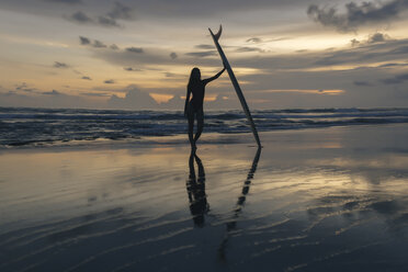 Silhouette einer jungen Frau mit Surfbrett am Strand gegen den Himmel bei Sonnenuntergang in voller Länge - CAVF53672