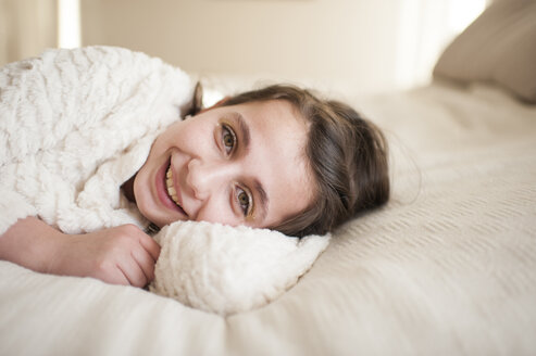 Portrait of smiling girl lying on bed at home - CAVF53682