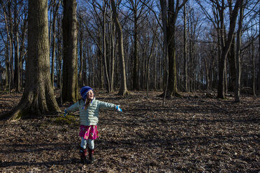 Glückliches Mädchen mit ausgestreckten Armen auf einem Feld im Wald stehend - CAVF53692
