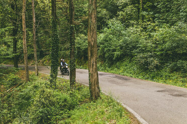 Motorrad fahrendes Paar auf einer Straße im Wald - CAVF53772