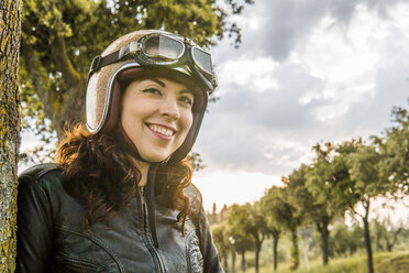 Low angle view of smiling woman standing against cloudy sky during sunset - CAVF53789