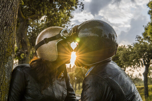 Romantisches Paar, das sich küsst, während es bei Sonnenuntergang vor dem Himmel steht - CAVF53791