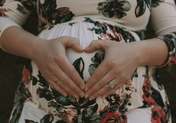 Midsection der schwangeren Frau macht Herzform auf ihren Bauch mit den Händen - CAVF53852