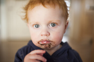 Porträt eines traurigen kleinen Jungen mit Essen im Mund zu Hause - CAVF53853