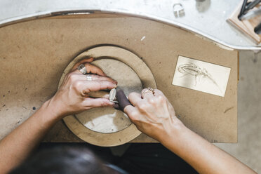 Cropped hands of female artisan making jewelry on wooden table in workshop - CAVF53901