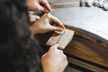 Abgeschnittene Hände eines Lehrers, der einem Schüler beibringt, einen Ring auf einem Tisch in einer Werkstatt herzustellen - CAVF53906