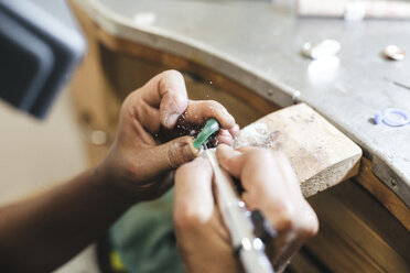 Abgeschnittene Hände einer Künstlerin, die einen Ring mit Ausrüstung auf einem Tisch in einer Werkstatt formt - CAVF53921