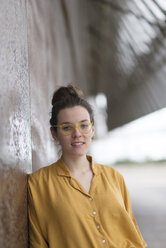 Porträt einer selbstbewussten Geschäftsfrau mit Brille, die an einer Wand steht - CAVF53941