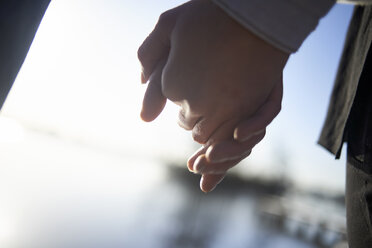 Cropped image of lesbian couple holding hands during sunset - CAVF53946