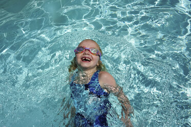 Hoher Winkel Blick auf glückliche Mädchen schwimmen im Pool in der Ferienanlage bei sonnigem Tag - CAVF53951