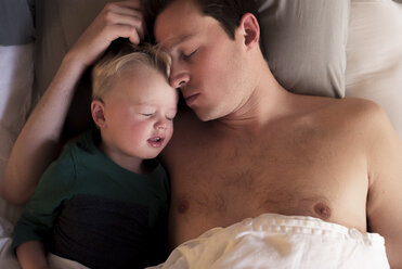 Hoher Blickwinkel des Vaters mit seinem Sohn, der zu Hause auf dem Bett schläft - CAVF53979