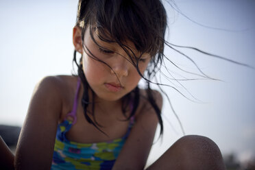 Low angle view of girl in swimwear crouching against clear sky during sunset - CAVF53988