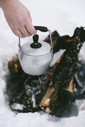 Abgeschnittene Hand hält Kessel über Lagerfeuer im Winter - CAVF53990