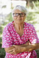 Portrait of senior woman with arms crossed wearing eyeglasses at backyard - CAVF53997