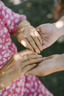 Nahaufnahme der Großmutter, die die Hände ihrer Enkelin im Hinterhof hält - CAVF54000