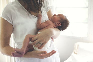 Midsection of mother carrying newborn daughter at home - CAVF54016