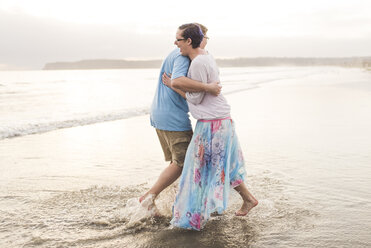 Seitenansicht eines glücklichen Paares, das sich umarmt, während es am Strand steht - CAVF54026