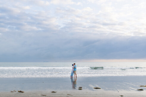 Verliebtes Paar steht am Strand gegen bewölkten Himmel - CAVF54028
