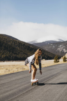 Unbeschwerte junge Frau beim Skateboarden auf der Straße an einem sonnigen Tag in voller Länge - CAVF54029