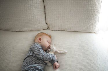 High angle view of cute baby boy sleeping with stuffed toy on bed - CAVF54043