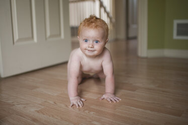 Porträt des niedlichen hemdlosen Babyjungen, der zu Hause auf dem Boden krabbelt - CAVF54044