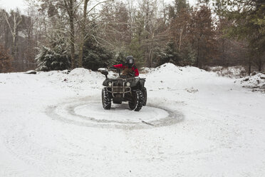 Jugendlicher fährt Quad auf einem verschneiten Feld - CAVF54048