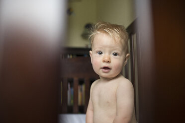 Porträt eines kleinen Jungen ohne Hemd, der zu Hause in seinem Kinderbett sitzt - CAVF54085