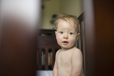 Portrait of shirtless baby boy sitting in crib at home - CAVF54085