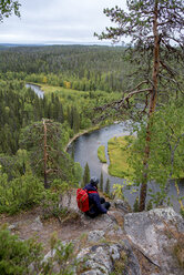 Finnland, Oulanka-Nationalpark, Frau mit Rucksack in unberührter Natur sitzend - PSIF00154