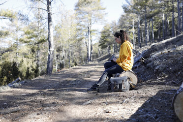 Young woman with yellow sweater in the forest, writing - GRSF00002