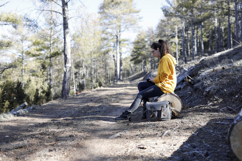 Junge Frau mit gelbem Pullover im Wald, schreibend - GRSF00002