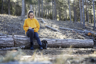 Young woman with yellow sweater in the forest, writing - GRSF00003