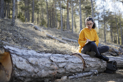 Young woman with yellow sweater in the forest, writing stock photo