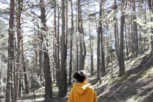 Rückansicht einer jungen Frau mit gelbem Pullover im Wald - GRSF00009