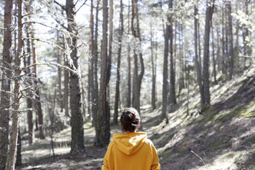Rückansicht einer jungen Frau mit gelbem Pullover im Wald - GRSF00010