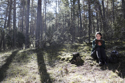 Young woman sitting in the forest, writing stock photo