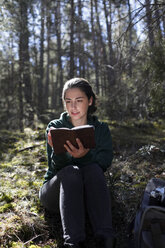Junge Frau mit gelbem Pullover im Wald, schreibend - GRSF00013