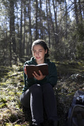 Young woman with yellow sweater in the forest, writing - GRSF00013