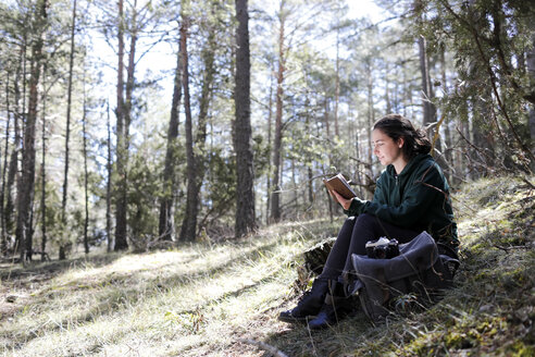 Young woman with yellow sweater in the forest, writing - GRSF00014