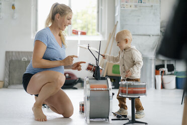 Happy pregnant mother with toddler son playing toy drums - KNSF05197