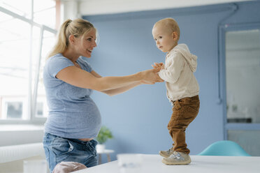 Pregnant mother with toddler son standing on table - KNSF05200