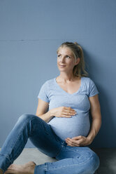 Porträt einer lächelnden schwangeren Frau, die auf dem Boden sitzt - KNSF05208