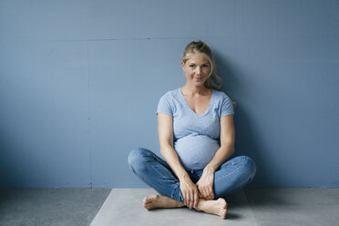 Porträt einer lächelnden schwangeren Frau, die auf dem Boden sitzt - KNSF05213