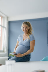 Porträt einer lächelnden schwangeren Frau mit Tablet - KNSF05218